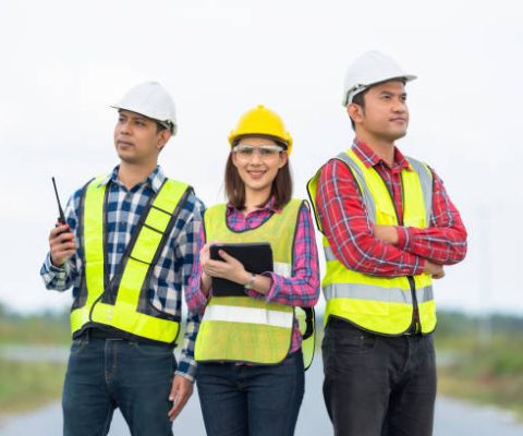 Photo of a team of 3 engineers or architects, male and female, smiling, smart, wearing uniforms and helmets. Stand together in strength and unity. ready to work on industrial structures